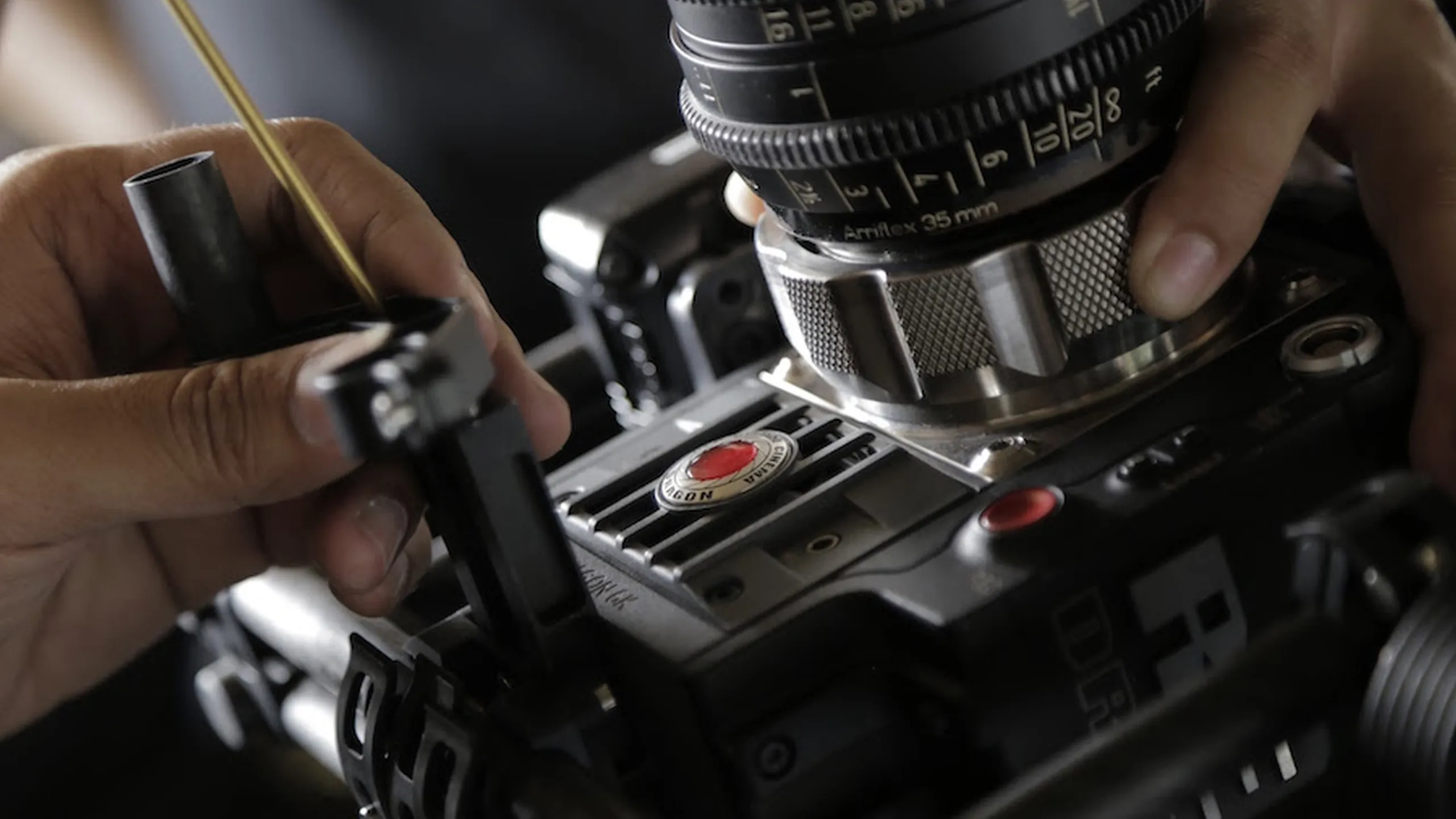 ผู้ช่วยช่างกล้องกำลังใส่เลนส์ถ่ายภาพยนตร์บนกล้อง RED