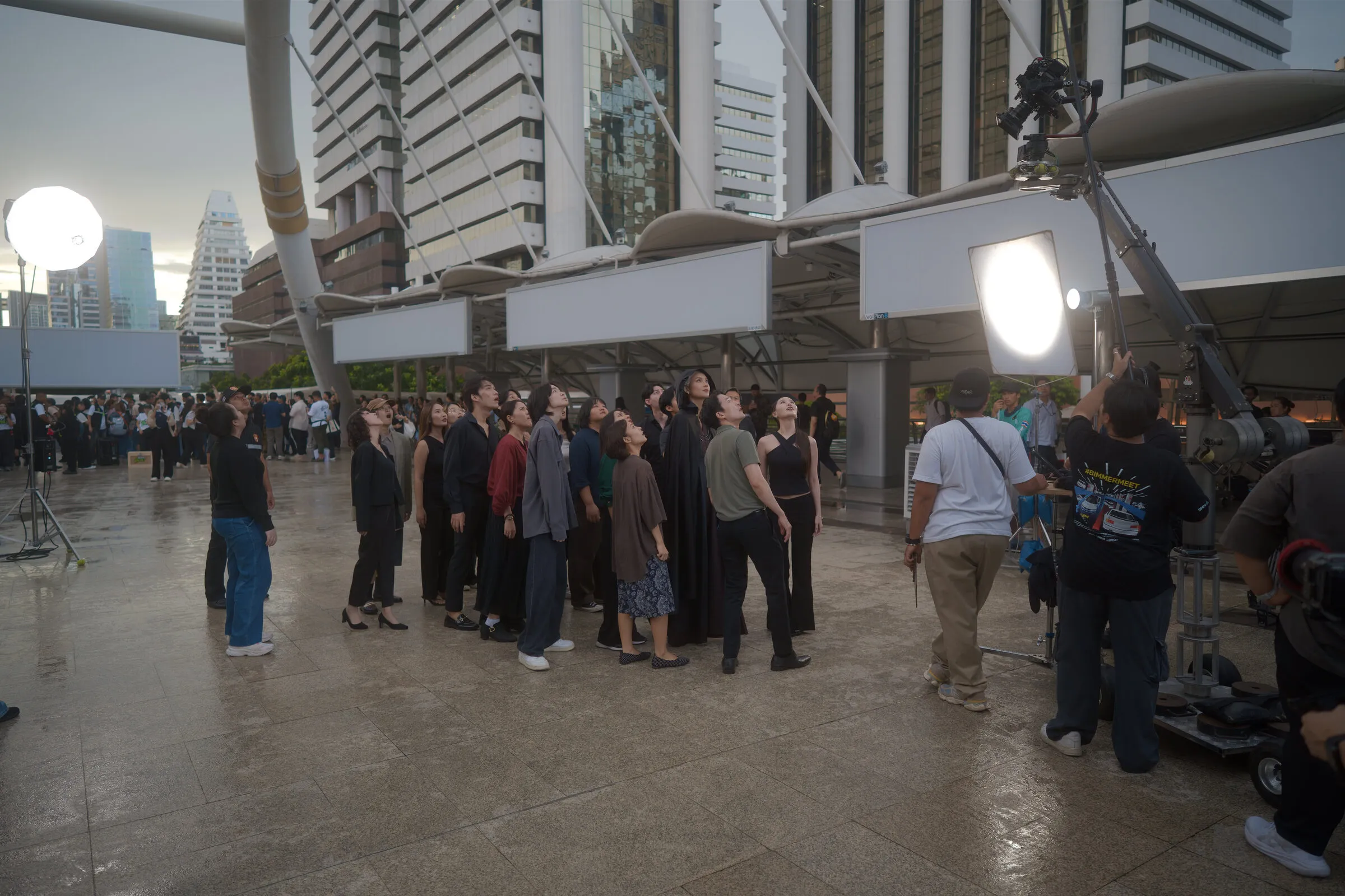Cast in costume waiting on a city plaza location at dusk, with a balloon light