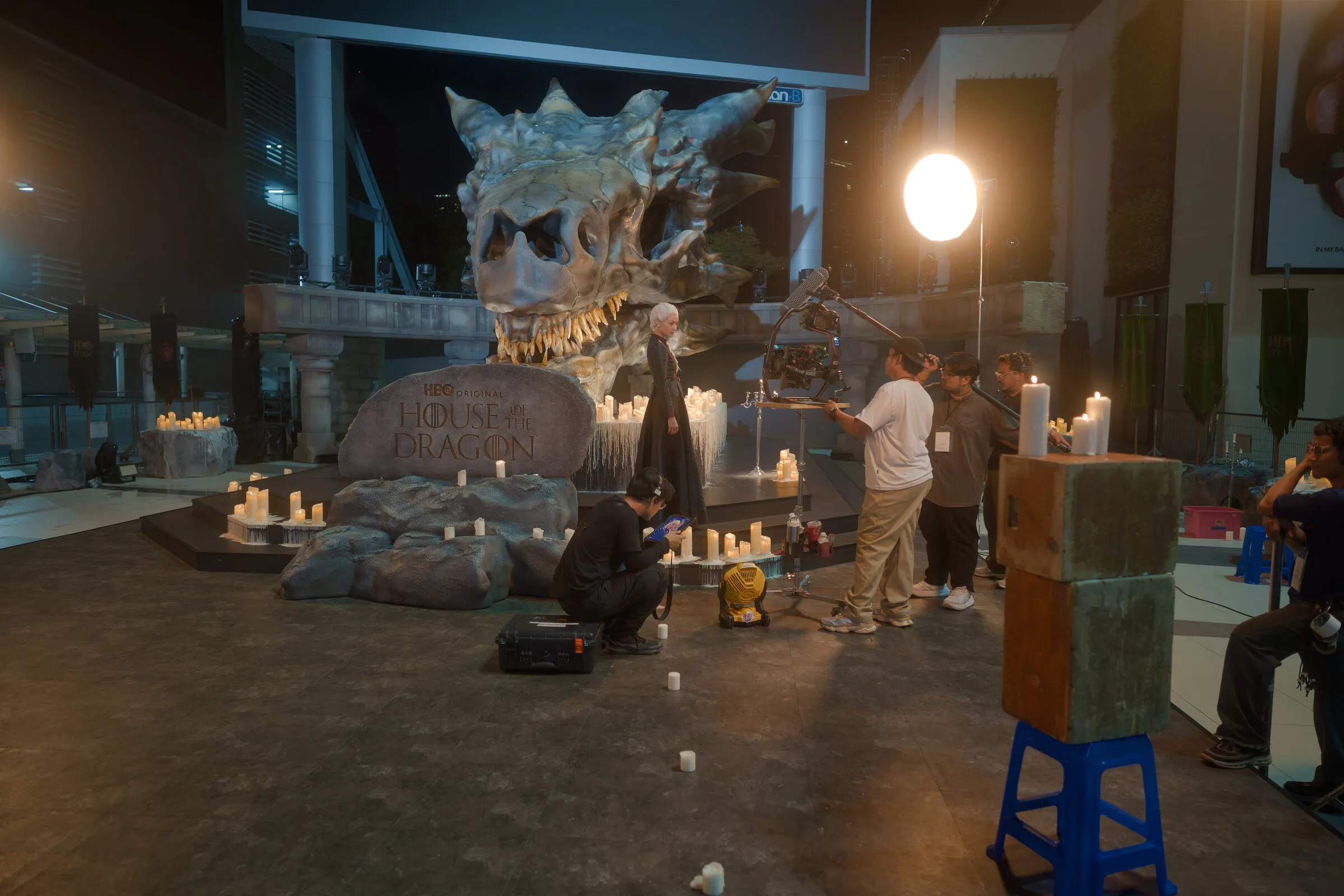 Night set with a giant dragon skull, stone props and candles, and the crew at work
