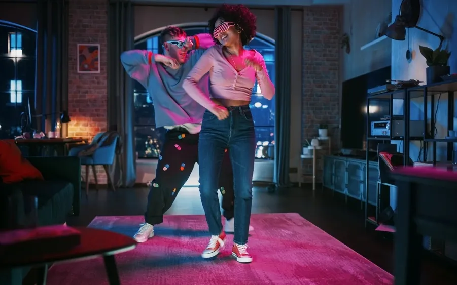Two young people dancing in a living room