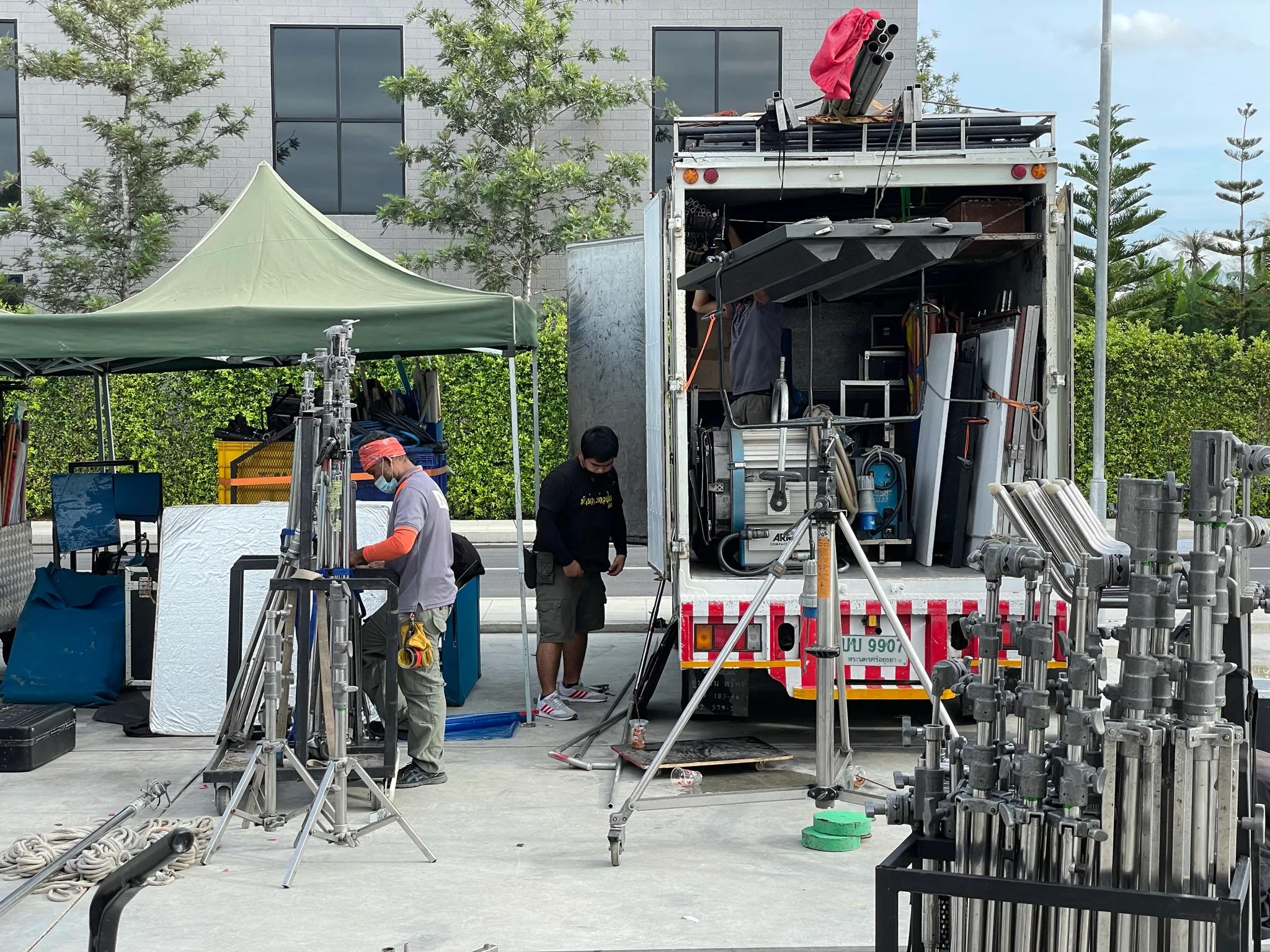 Grip and lighting truck unloaded at a location, with stands and a tent