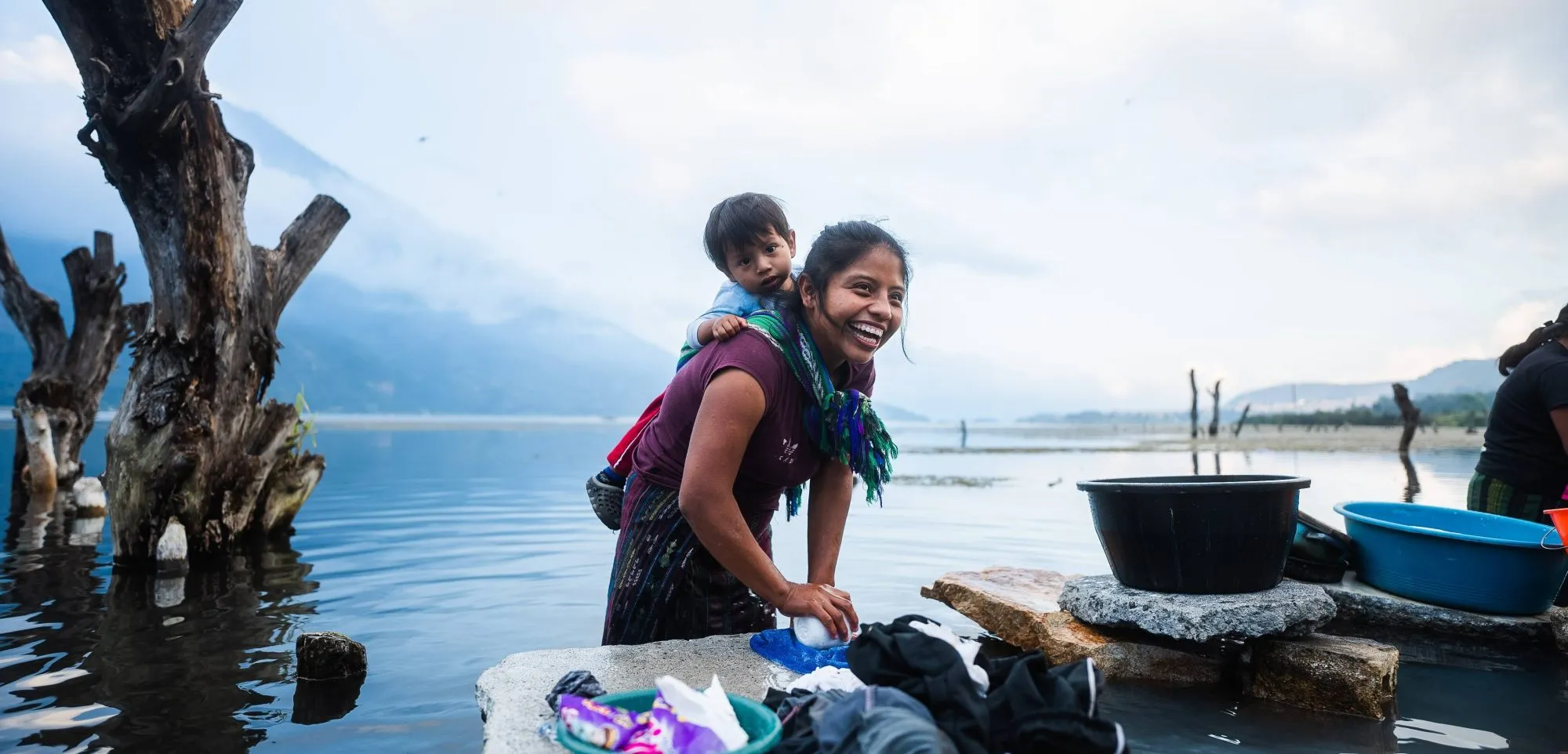Woman and child washing clothes at a lake shore, filmed for a documentary
