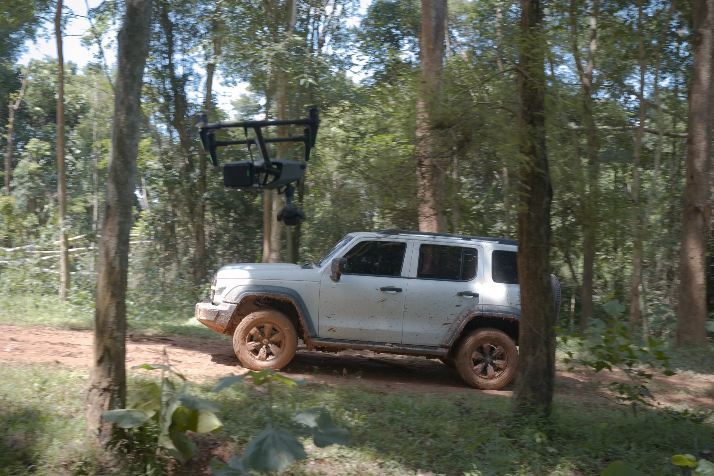 DJI Inspire 3 drone tracking a pickup truck along a forest track in Thailand