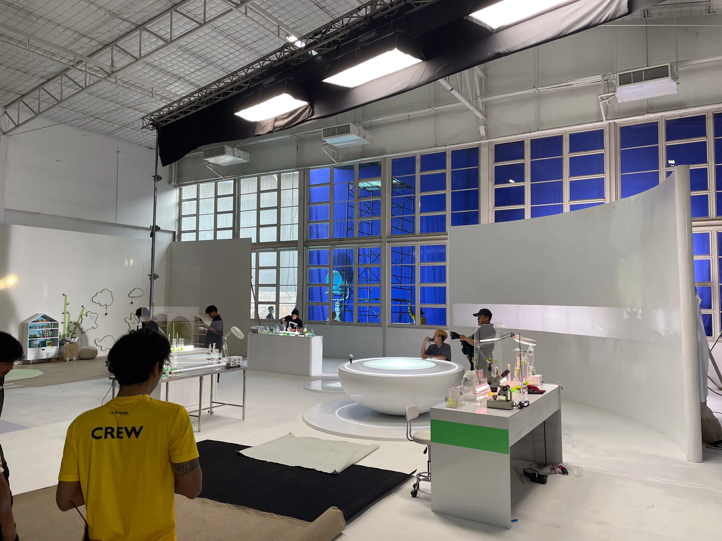 Studio set build for a Molfix commercial: curved white walls and a bath, with a crew member walking through