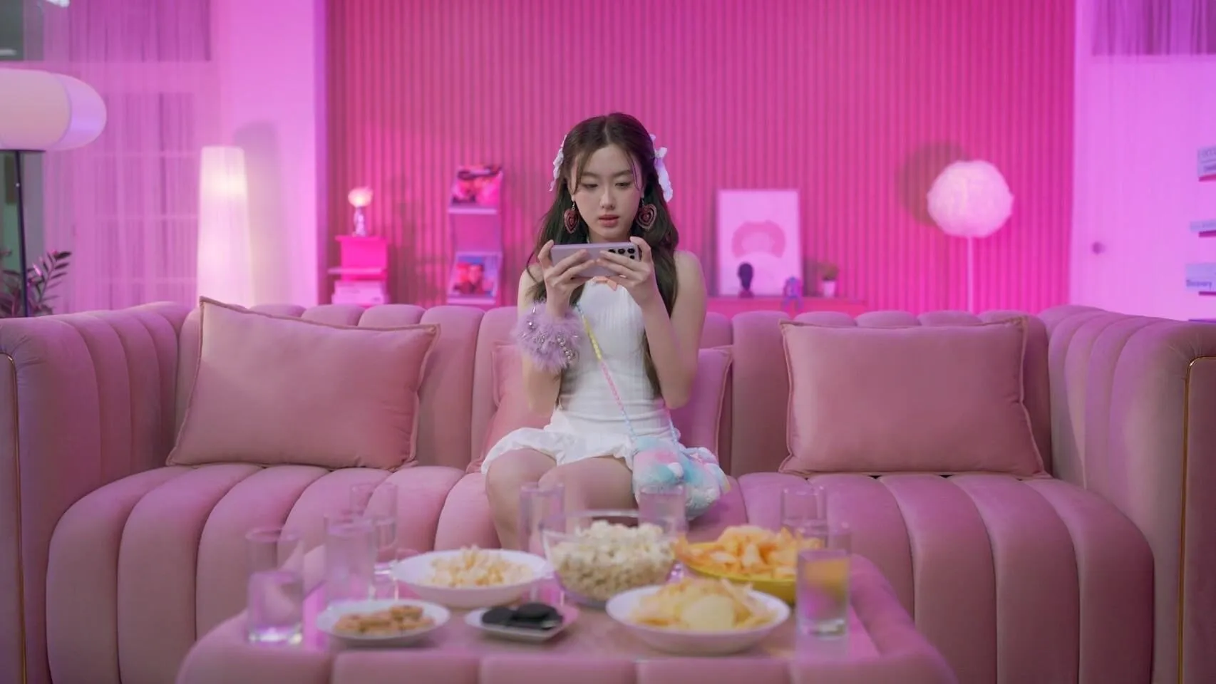Finished pink set with a sofa, lamps and snacks, and an actress on the sofa