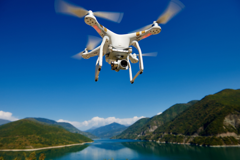 uav drone with high resolution digital camera flying in the blue sky over the mountain at lake for a drone survey